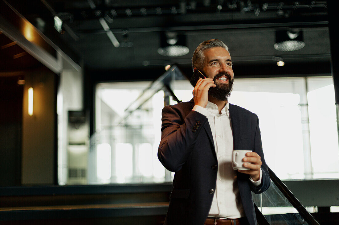 Geschäftsmann, der in einem Café mit einem Handy telefoniert