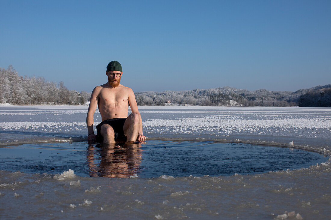 Man swimming in frozen lake