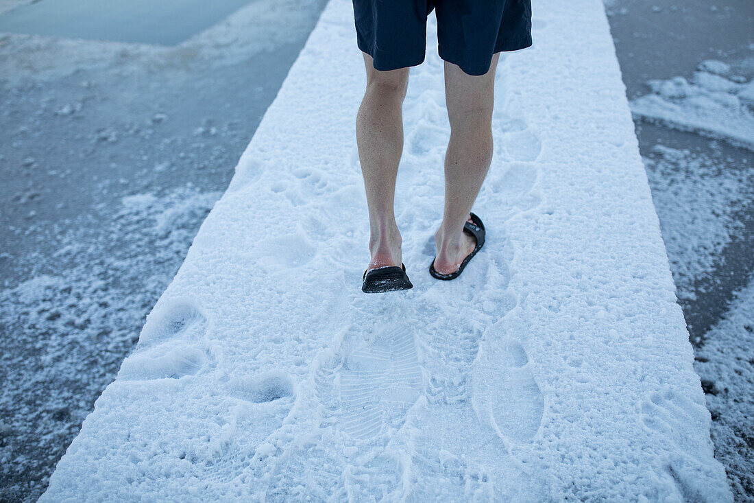Flachbild einer Frau, die auf einem zugefrorenen See spazieren geht