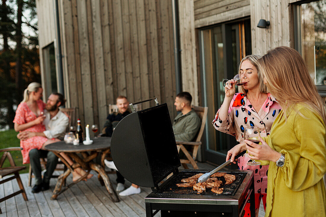 Freunde beim Grillen und Weintrinken auf der Veranda