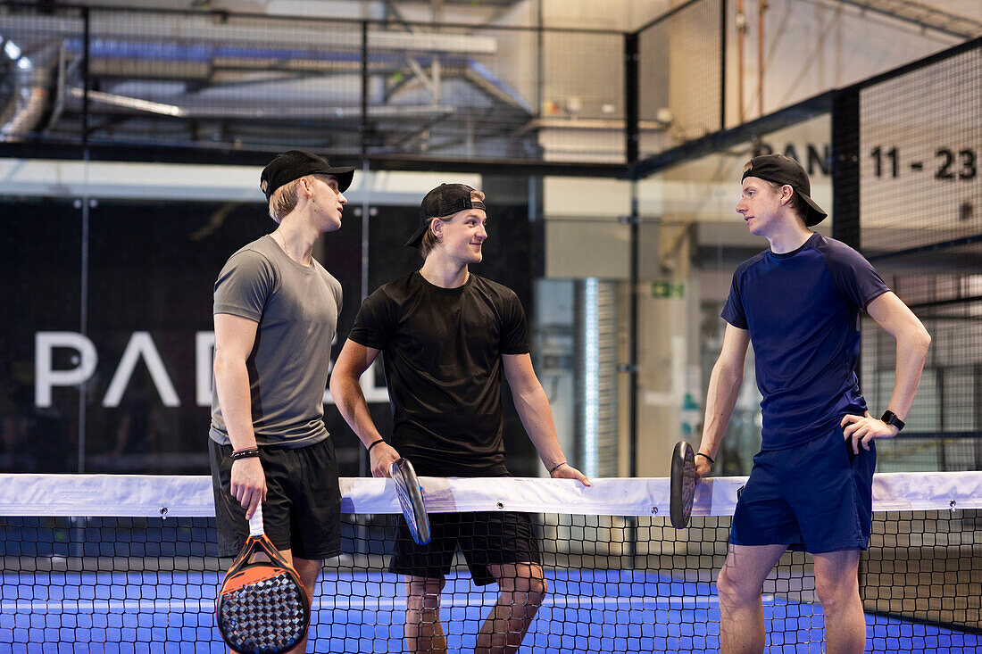 Männer unterhalten sich auf einem Indoor-Padelplatz