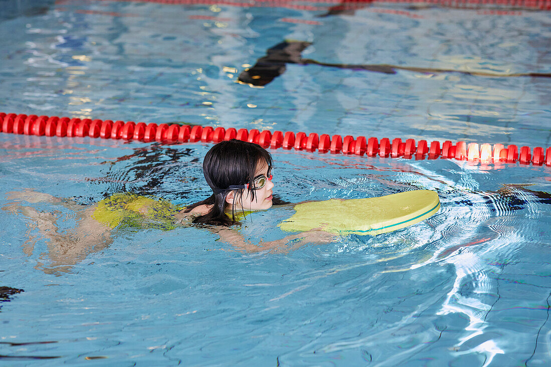 Mädchen lernt im Hallenbad schwimmen