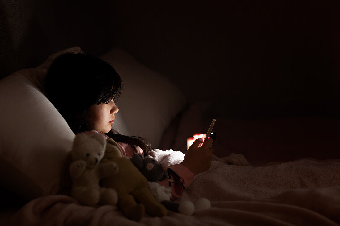 Girl in bed using cell phone