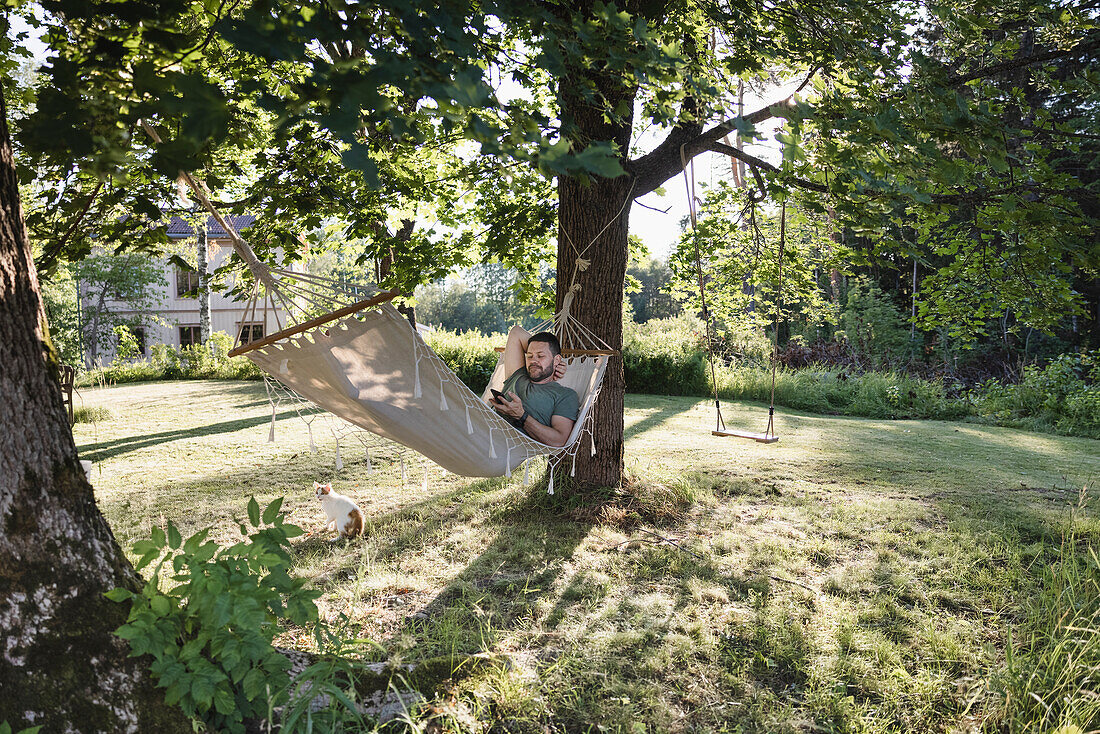 Mann liegt in Hängematte im Garten