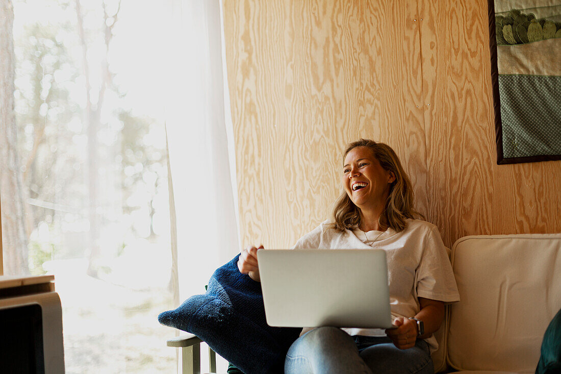 Happy woman using laptop on sofa