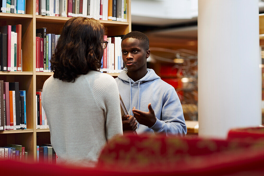 Zwei Studenten unterhalten sich in der Bibliothek