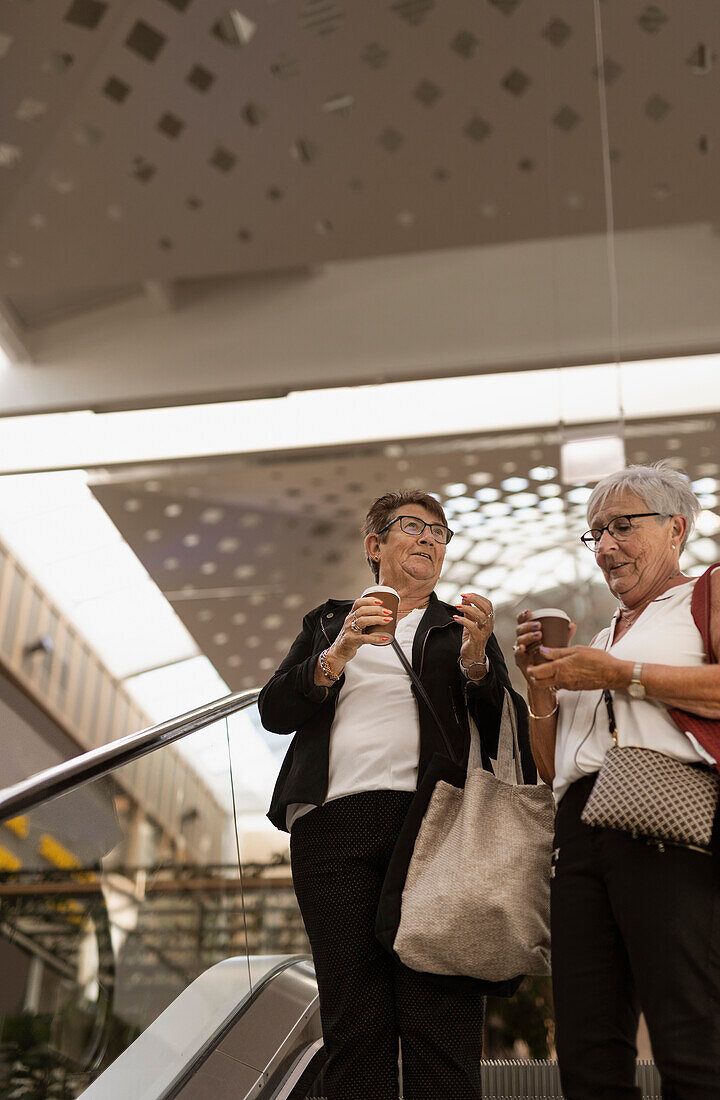 Lächelnde Frauen auf Rolltreppe