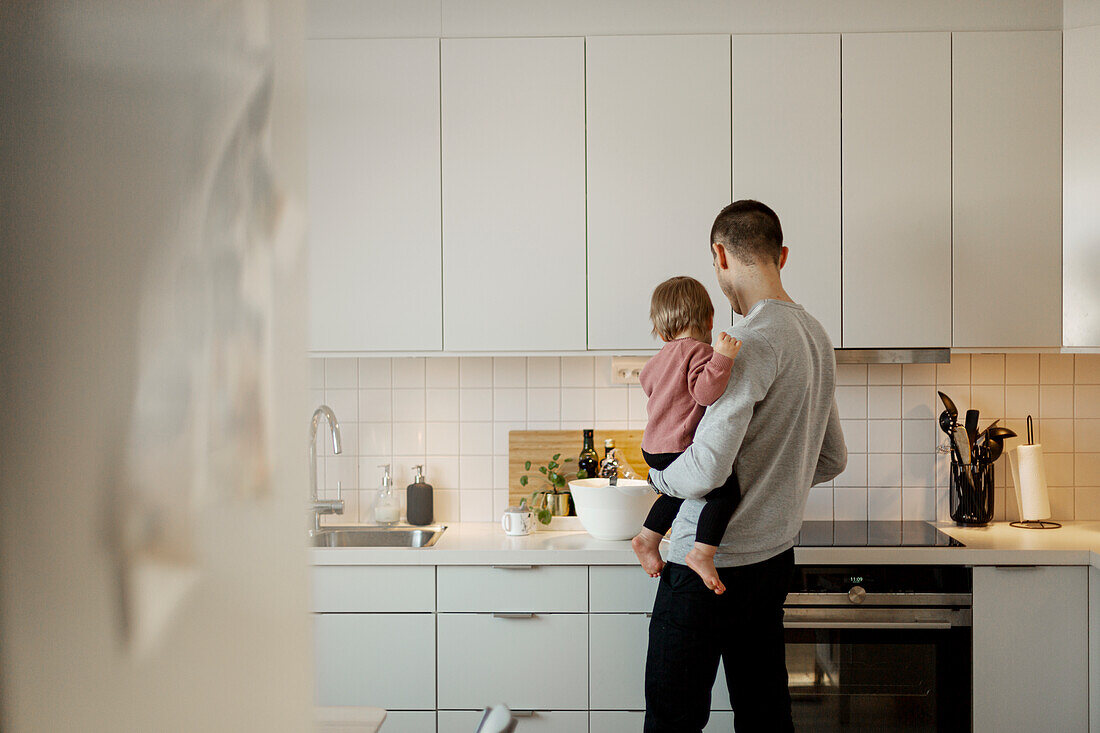 Vater trägt kleines Mädchen in der Küche