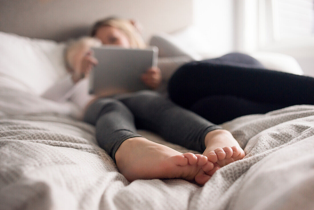 Mother and daughter using tablet in bed
