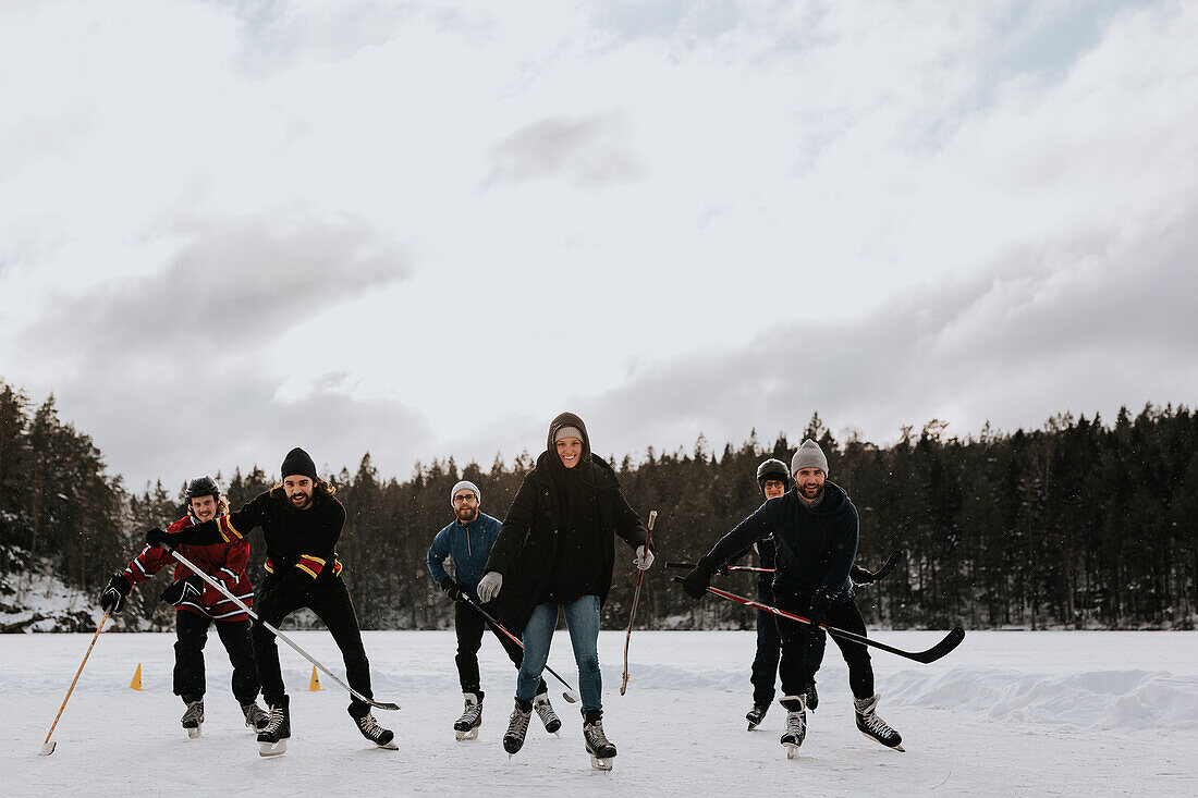 Freunde spielen Hockey auf gefrorenem See