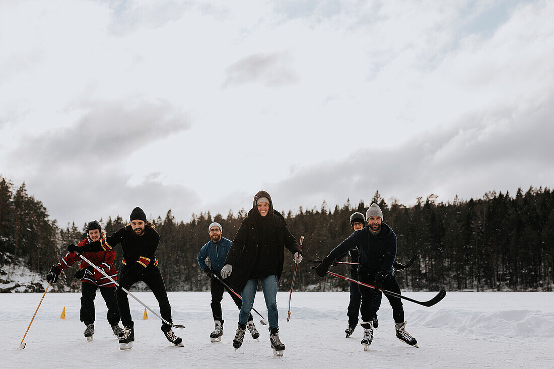 Friends playing hockey on frozen lake