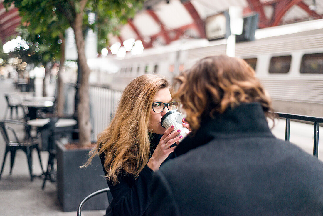 Man and woman drinking coffee at train station