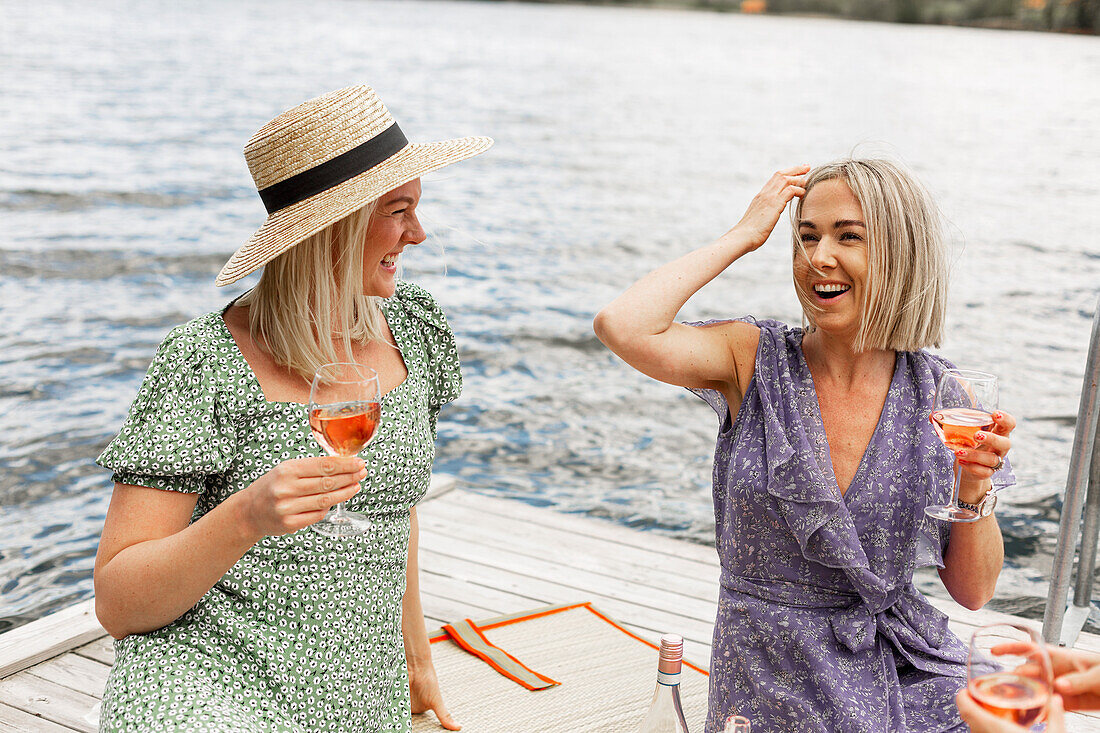 Female friends having wine on jetty