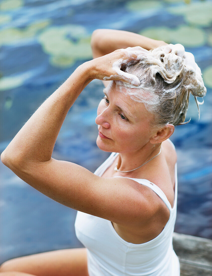 Frau wäscht ihr Haar am See