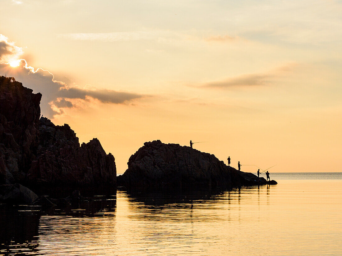 Silhouette of fishermen on shore at sunset