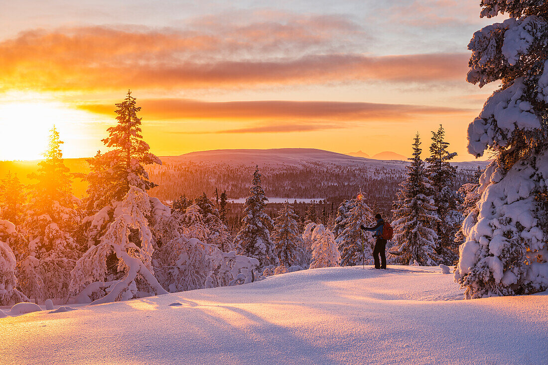 Wanderer im verschneiten Wald bei Sonnenuntergang