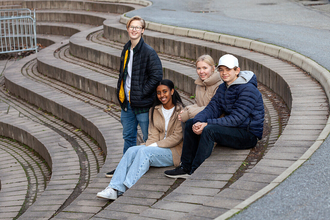 Porträt von lächelnden Teenager-Freunden, die auf einer Treppe sitzen