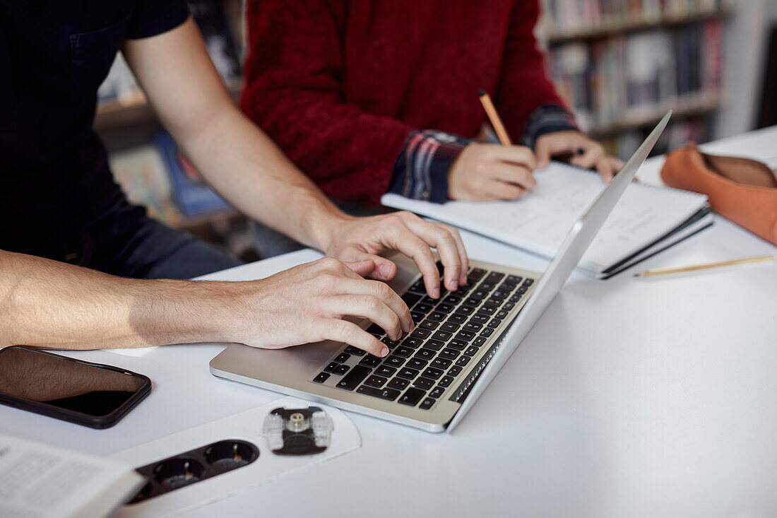 Schüler, die einen Laptop benutzen und Notizen machen