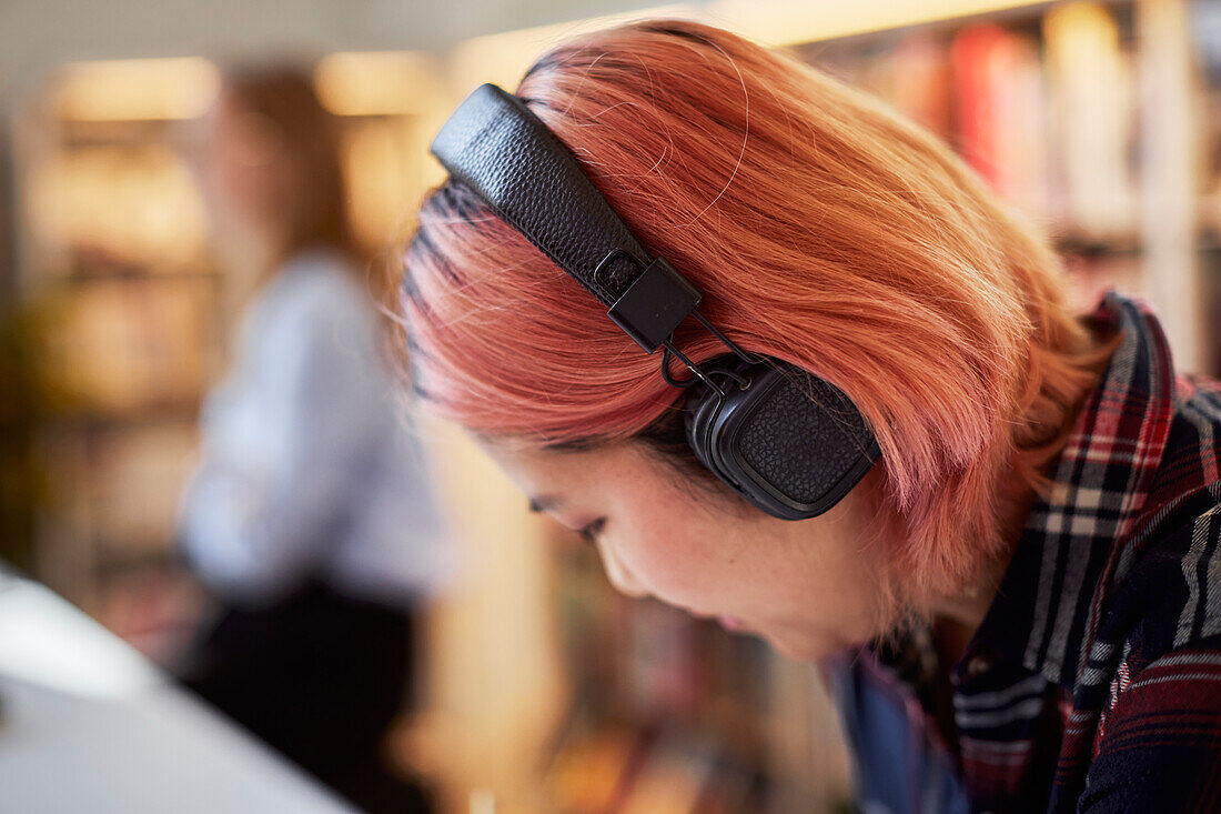 Studentin hört in der Bibliothek Musik
