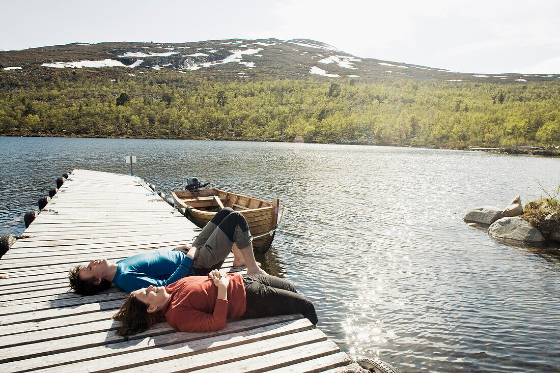 Hiking couple lying on jetty and sunbathing