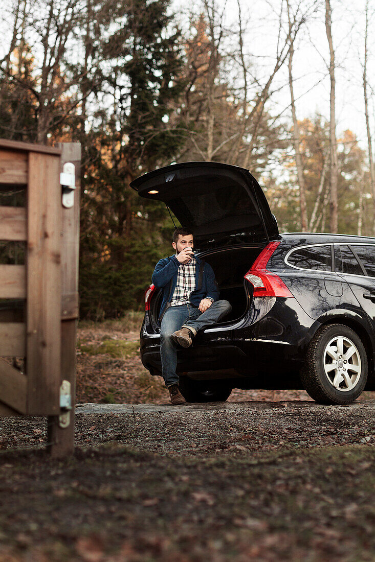 Man sitting in open car boot