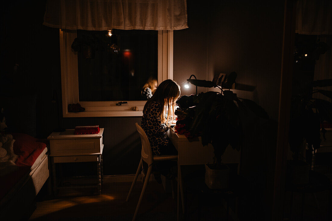 Mädchen bei Nacht am Schreibtisch sitzend