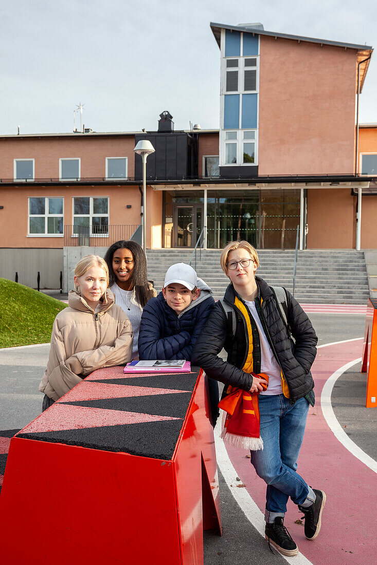 Portrait of teenage friends standing in front of school