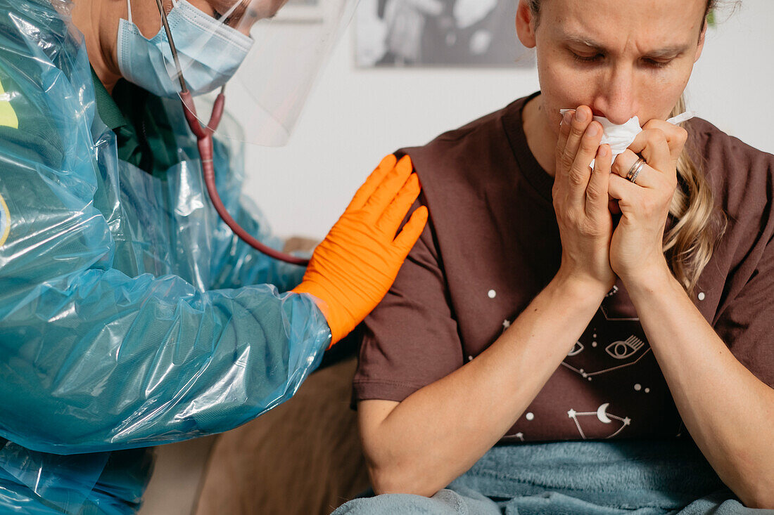 Arzt mit Stethoskop bei der Untersuchung eines Patienten zu Hause