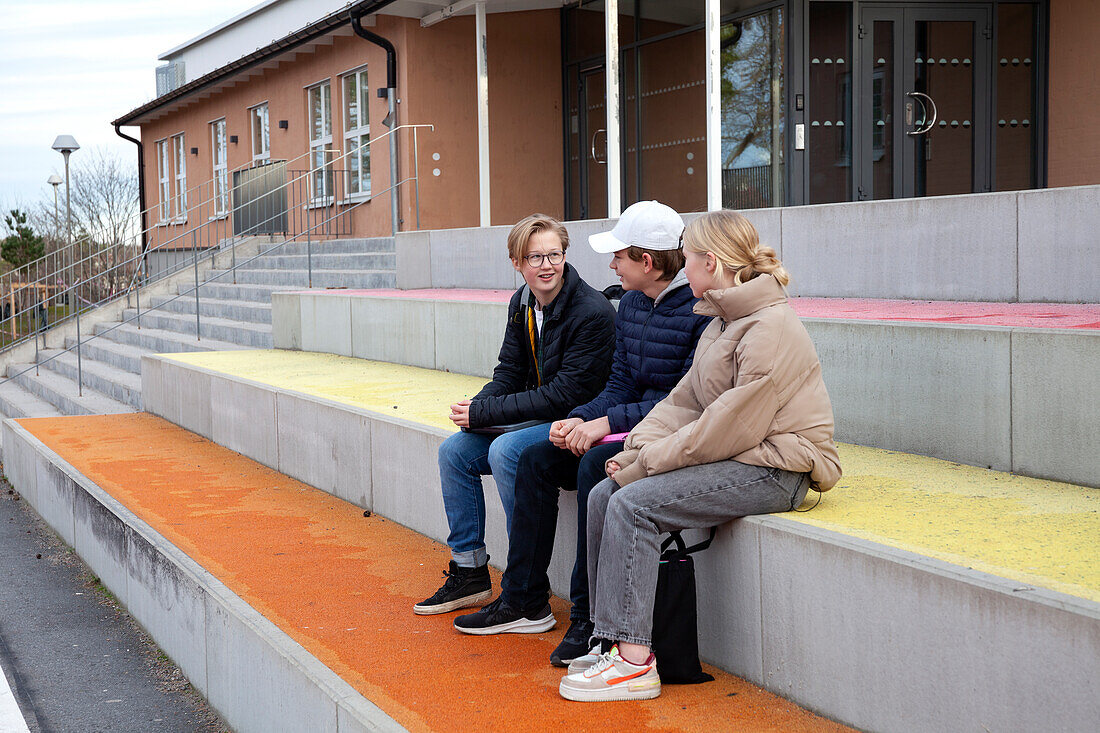 School friends sitting in front of school and talking