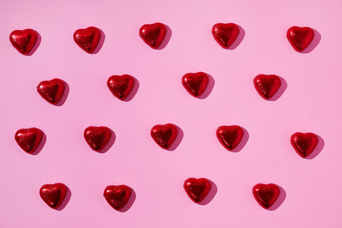 Heart-shaped candies on pink background