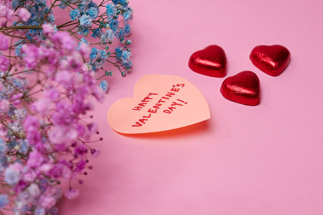 Heart-shaped candies and love message on pink background