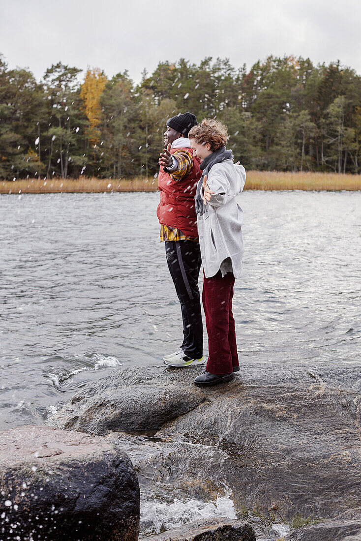 Friends standing on rocky lakeshore