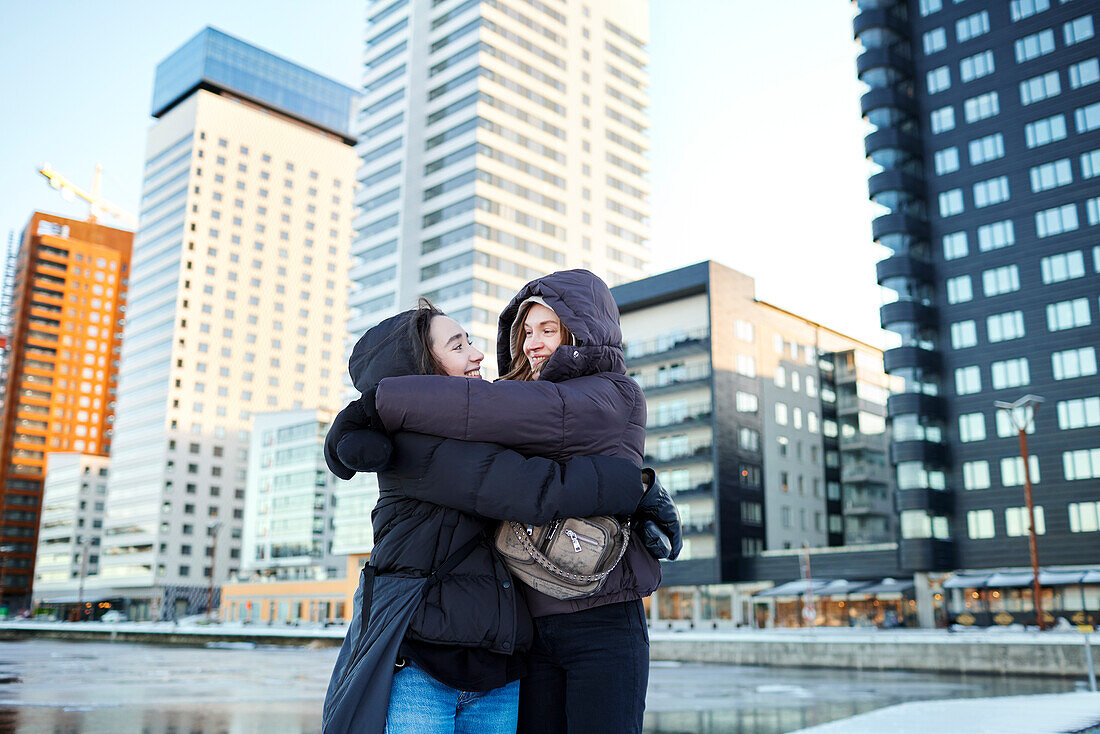 Young female couple hugging in modern neighborhood