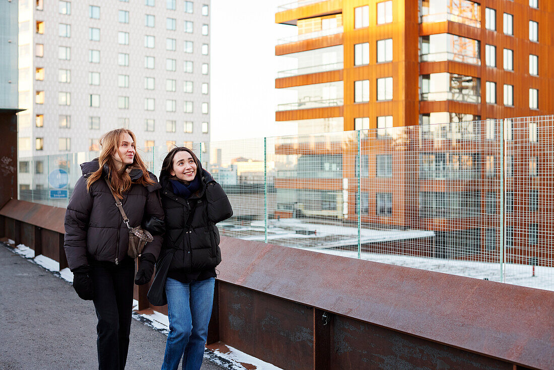 Smiling female couple walking in modern neighborhood