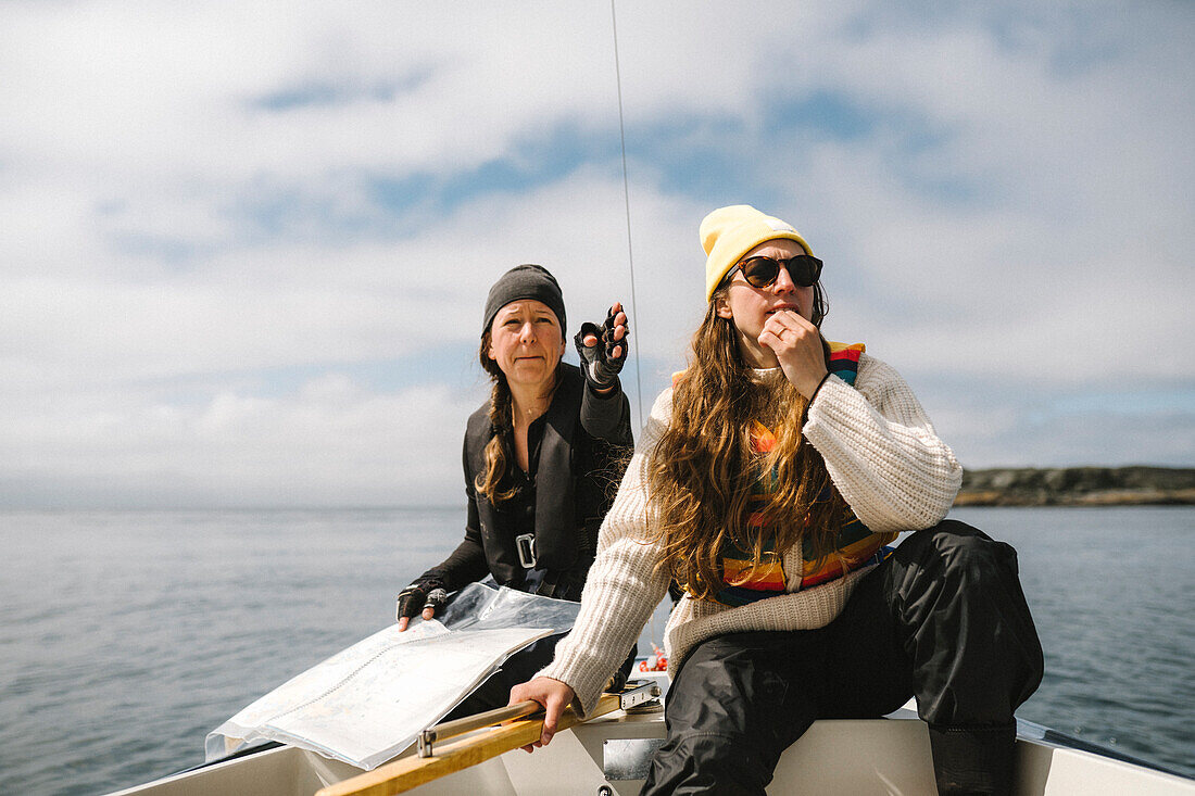 Frauen, die auf einem Boot sitzen und mit einer Karte die Richtung bestimmen