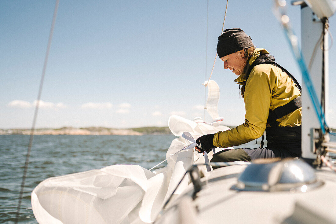 Frau faltet Segel auf Boot