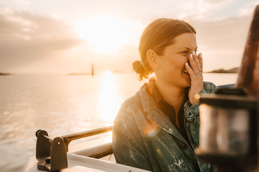 Junge Frau lacht bei Sonnenuntergang am Meer