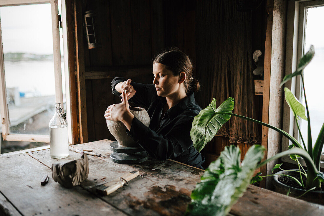 Female potter making vase in workshop