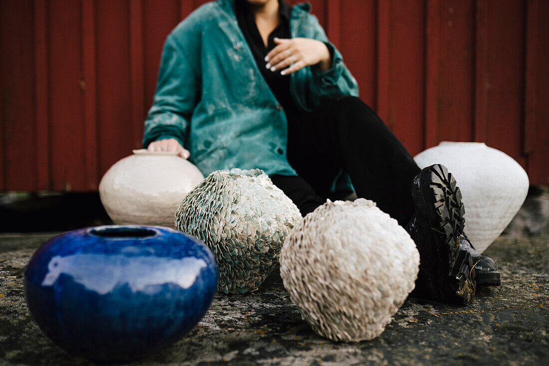Frau sitzt zwischen Keramikvasen