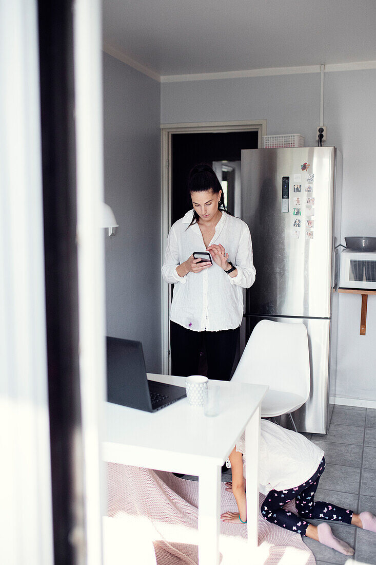 Woman in kitchen using cell phone