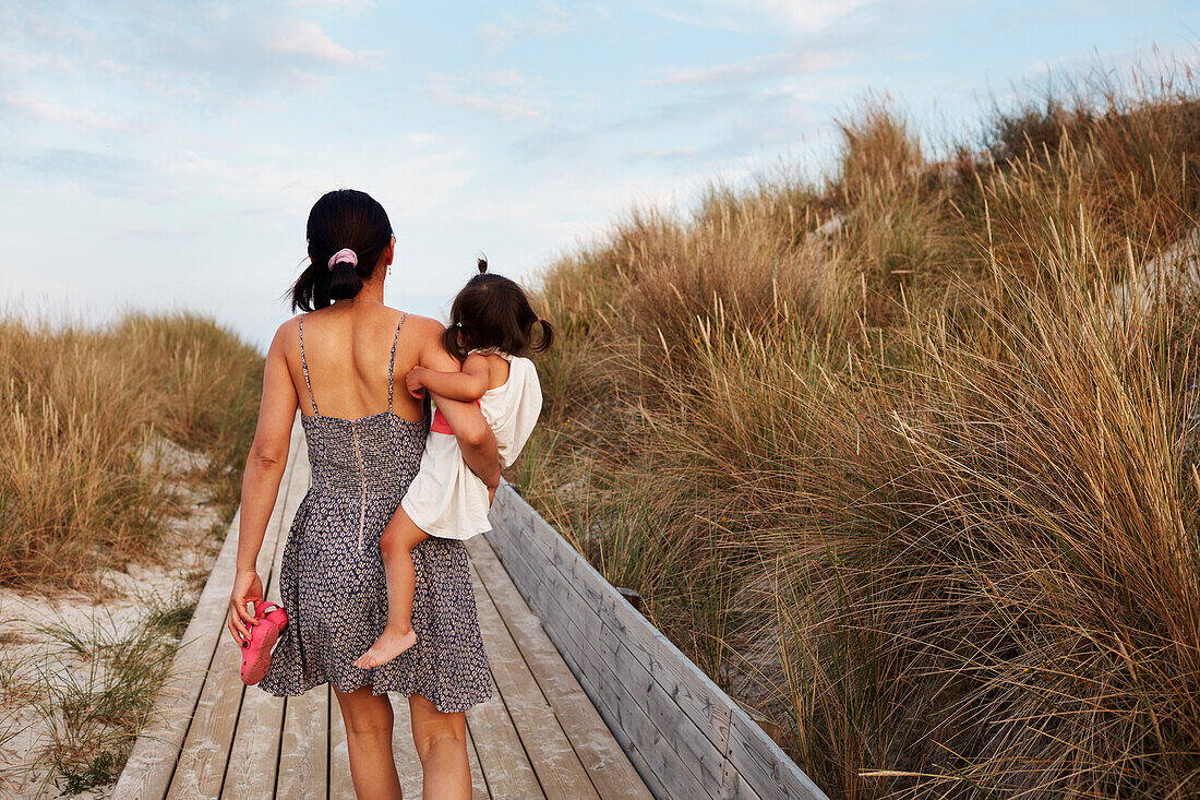 Rear view of woman carrying daughter