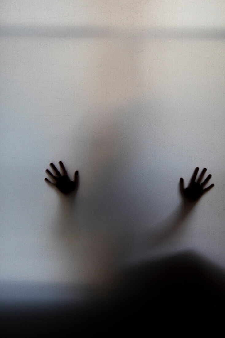 Child's hands pressed against frosted glass