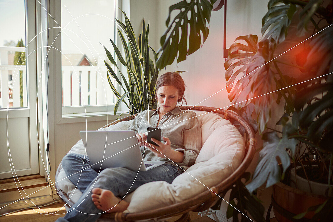 Woman using smart phone and laptop at home