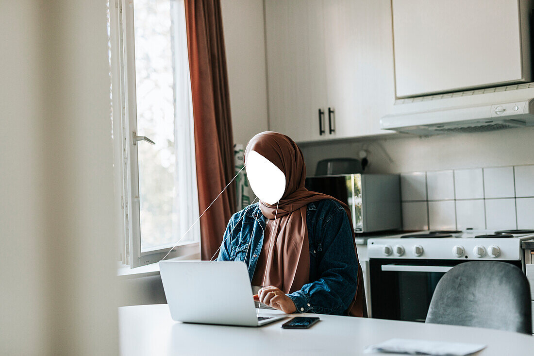 Faceless woman using laptop at home