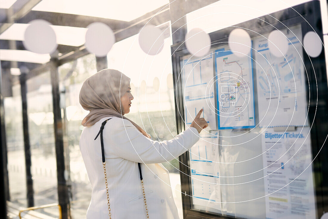Woman in headscarf looking at bus timetable