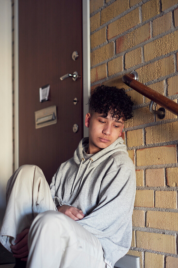 Junge sitzt auf einer Treppe und lehnt sich an eine Wand