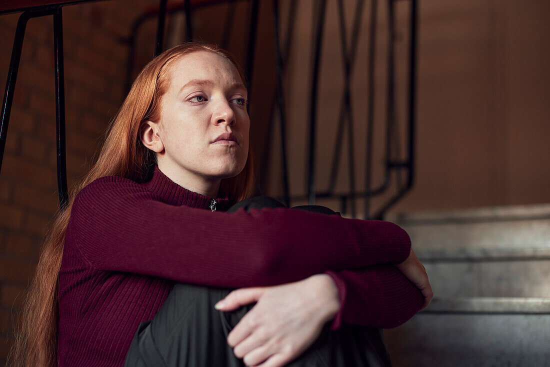 Young redhead woman sitting on stairs