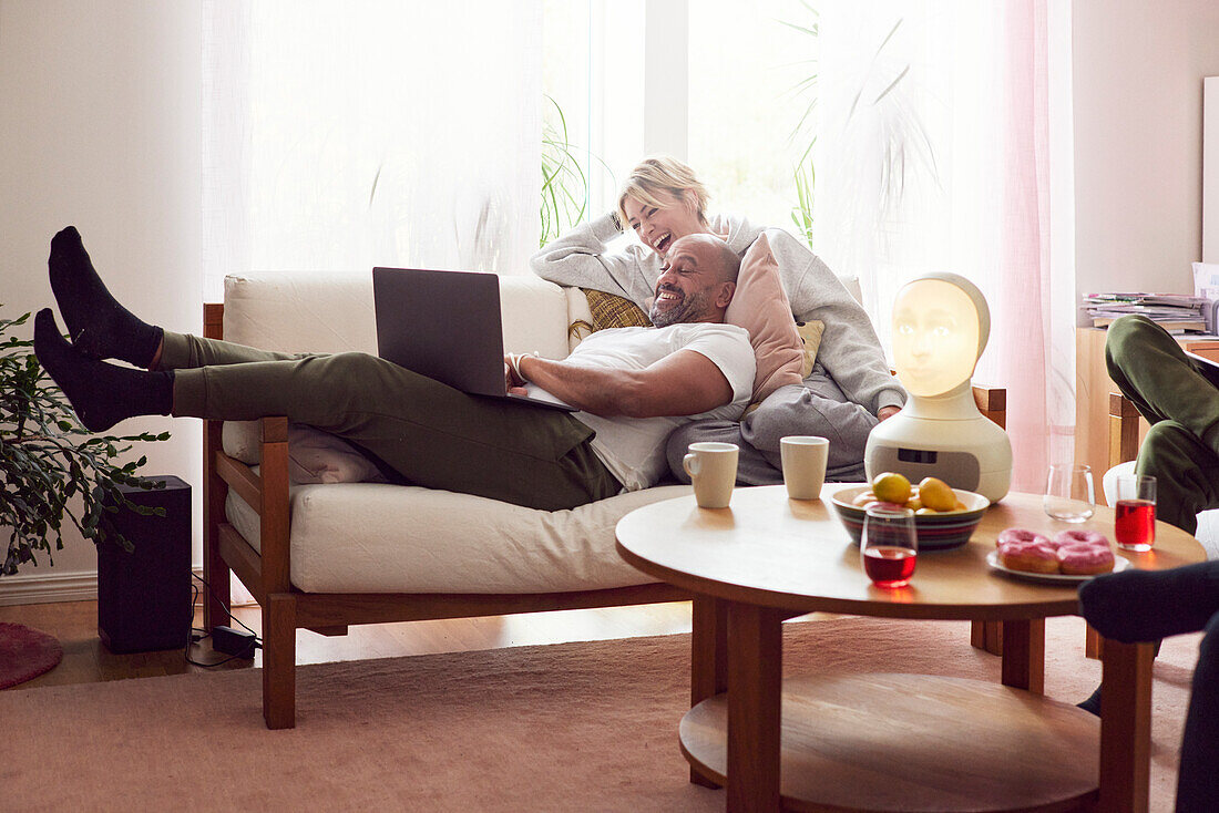 Smiling couple using laptop on sofa