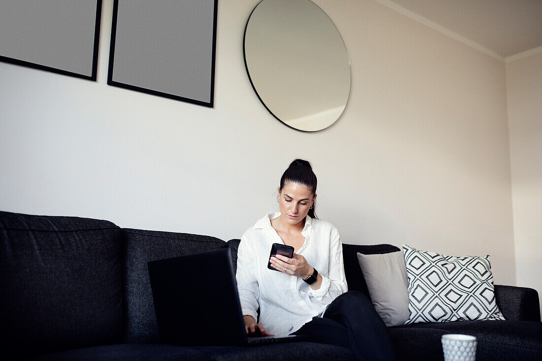 Frau auf dem Sofa mit Mobiltelefon