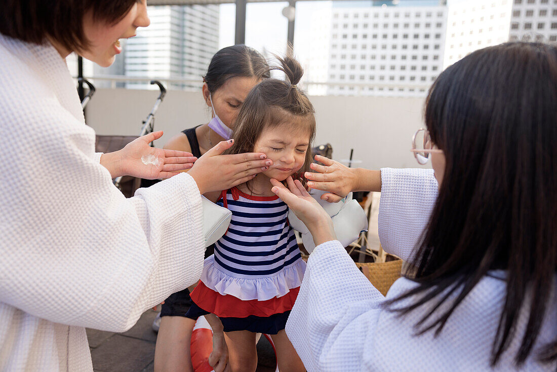 Women applying sunscreen on girl's face